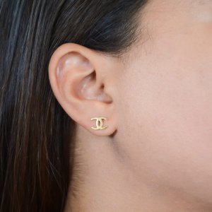 Χρυσά σκουλαρίκια 14Κ, με το λογότυπο γνωστού οίκου μόδας σε λείο λουστρέ φινίρισμα.
